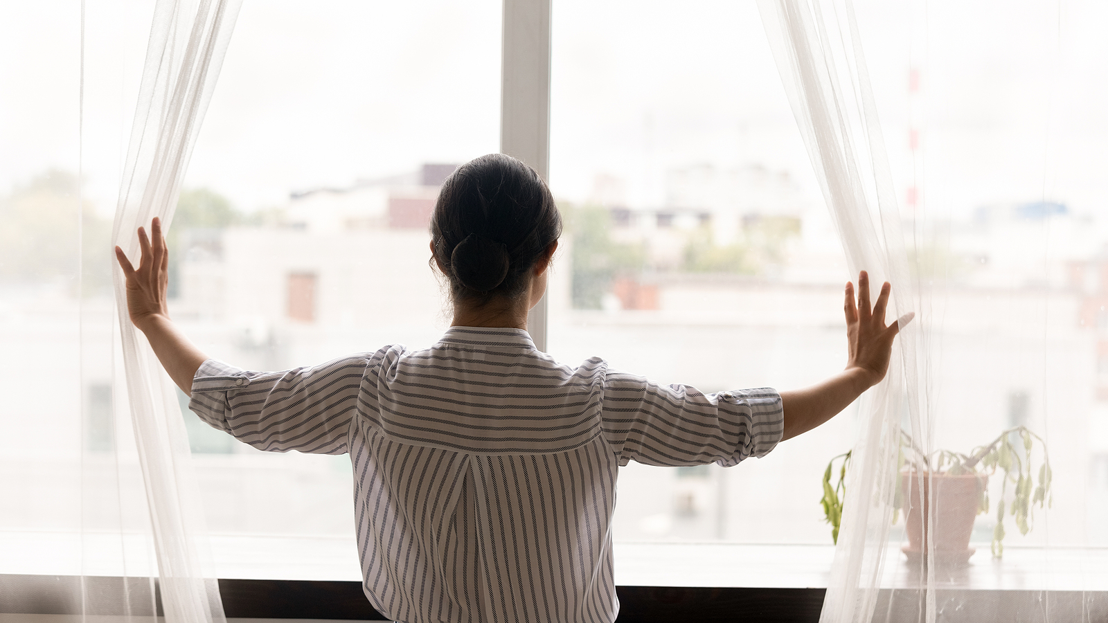 Woman stands in front of lardge window looking out at the world. PE therapy is shown to help treat PTSD effectively. Prolonged exposure therapy in Ohio is available to help!