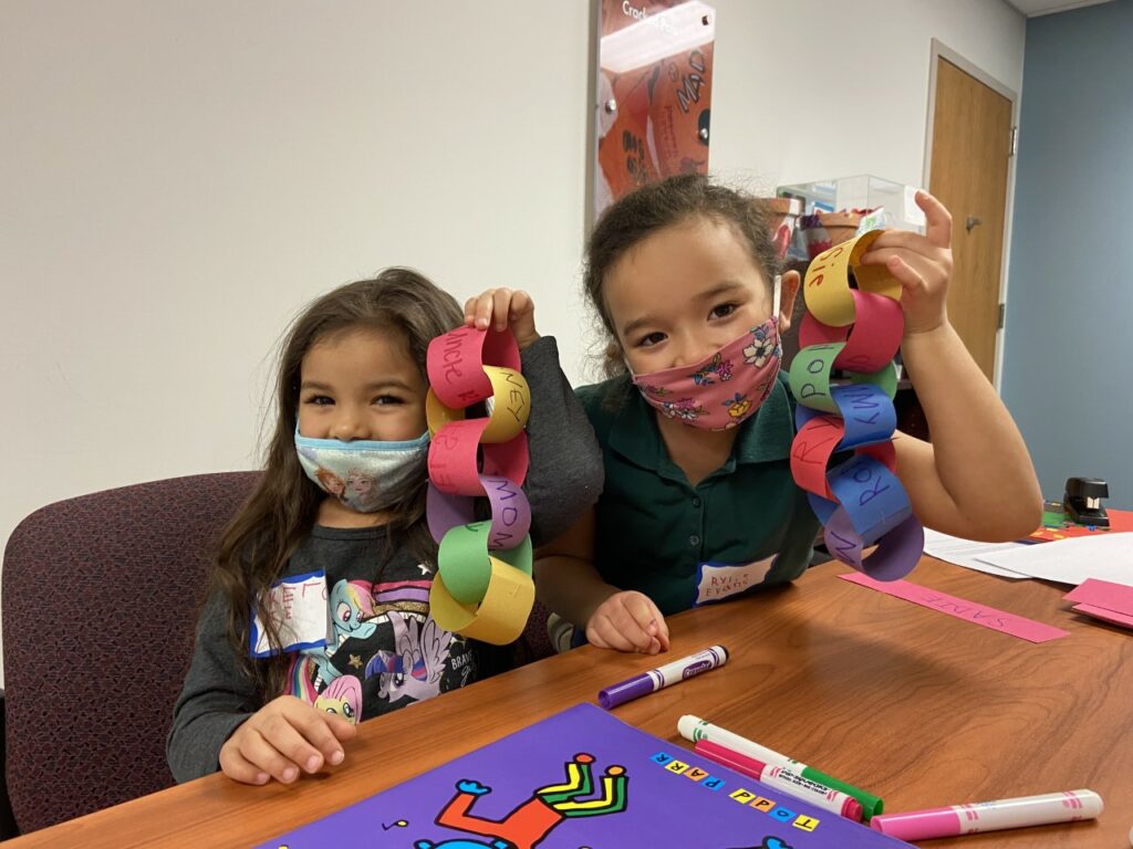 Two children creating paper chains as they process their grief over a lost loved one. If you are struggling with trauma online therapy in Ohio can help.