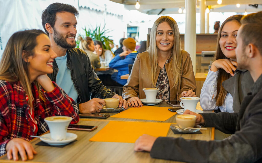 A group of friends dine together at a coffee shop, happy and relaxed. You too can find peace with the help of Online Trauma Therapy in Ohio, Kentucky, and New York. 