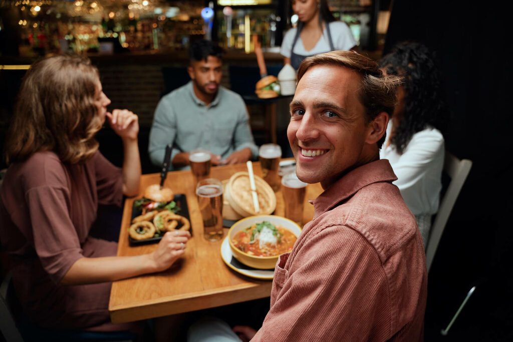 A group of friends dine out at a restaurant having a good time. You too can find happiness again with the help of Online PTSD Treatment in New York, Kentucky, and Ohio.
