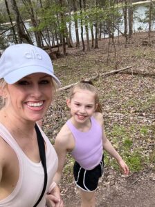 Jenn and her daughter smile at the camera while walking outdoors. Learn more about how an online therapist in Kentucky can offer support in Kentucky and Ohio. Contact a PTSD therapist for support with a family-centered approach. 