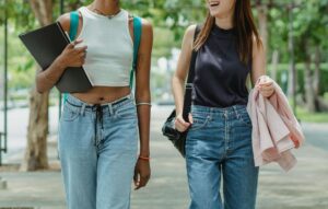 Two college-aged women walk and talk through a park, showing strength and resilience as sexual assault survivors in Ohio seeking therapy for sexual assault in Kentucky and support from a therapist for sexual trauma in Ohio. 