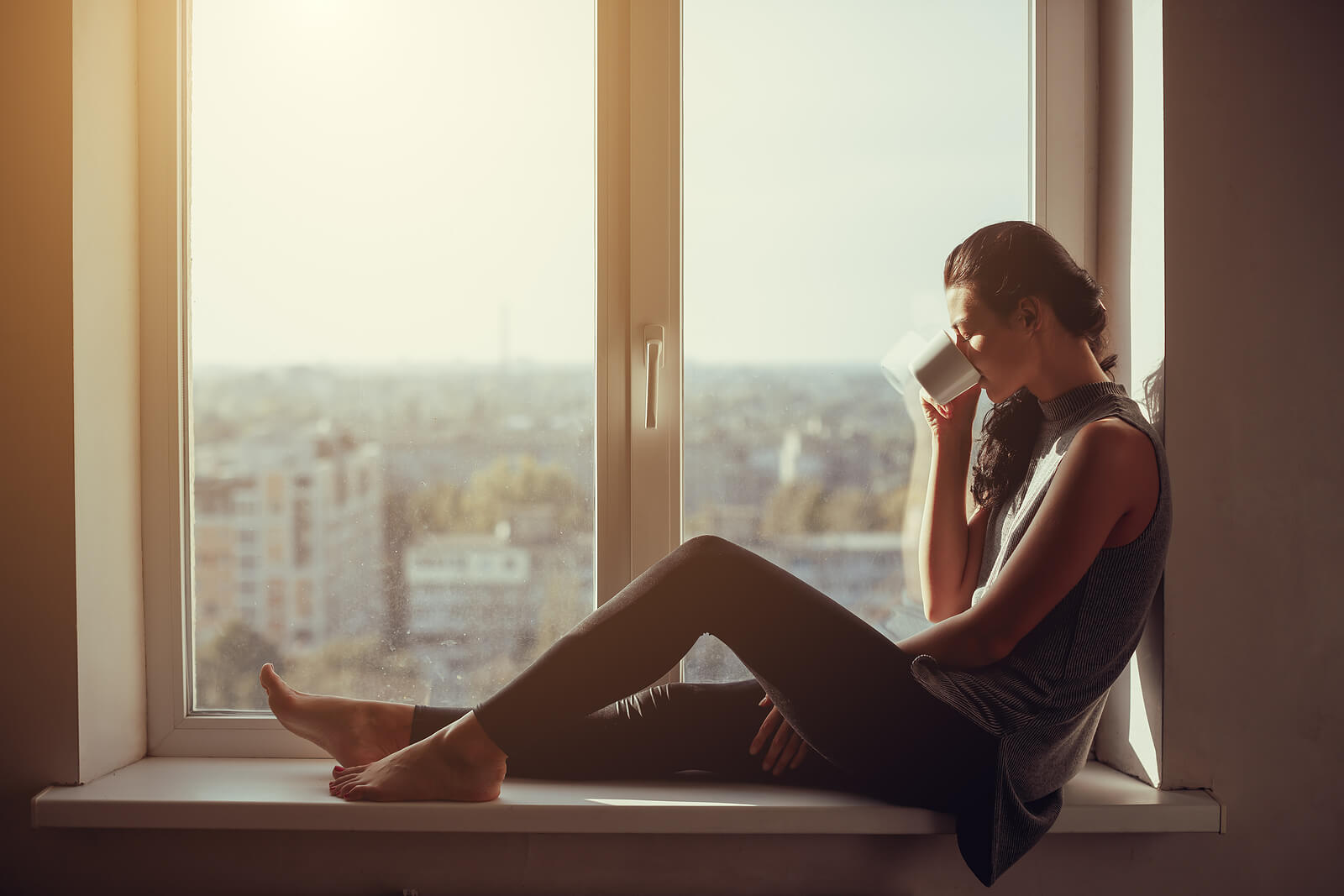 A person sits quietly by a sunlit window with a warm mug, taking a moment to breathe through the heaviness of loss. The image reflects the kind of support people often seek through grief counseling in ohio, especially when getting out of the house feels hard. For those who need flexibility, working with an online therapist in ohio through online therapy in ohio can be a gentle first step.