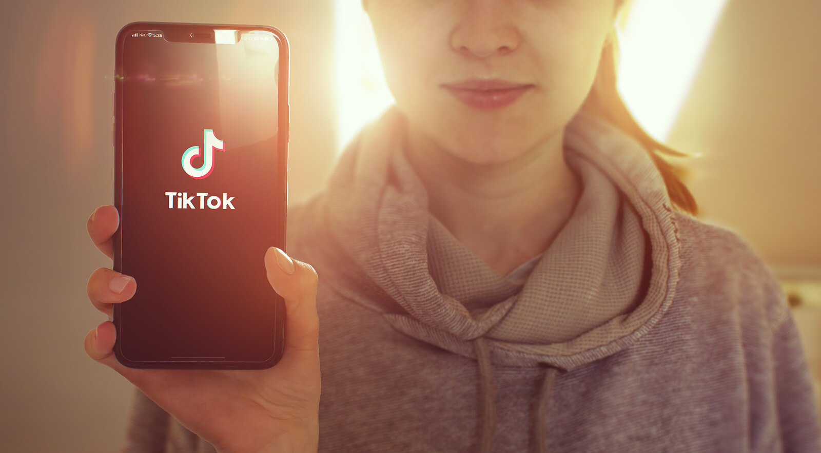 A young woman holds up a smartphone displaying the TikTok logo, representing the growing trend of seeking mental health information through short-form social media content. While these videos can offer a sense of validation, a trauma therapist in Cincinnati, OH understands that a 60-second clip cannot replace the personalized, clinical care that real healing requires. Trauma treatment in Cincinnati goes far beyond a label — it addresses the nervous system, the body, and the full context of a person's lived experience.
