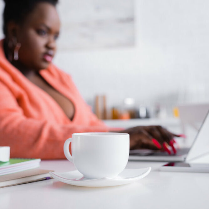 Cup Of Coffee And Saucer On Table Near African American Plus Siz